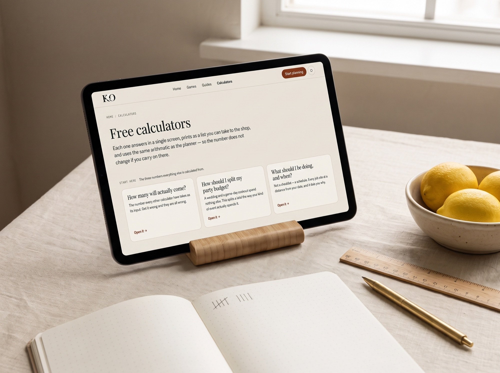 A tablet on a cream desk showing the calculators page, with an open notebook of tally marks, a wooden ruler and a bowl of lemons